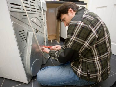 Repairman fixing a heating elelment on a domestic tumble dryer
